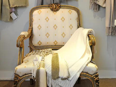 A gilded antique armchair with a cream throw inside Hartley Antiques
